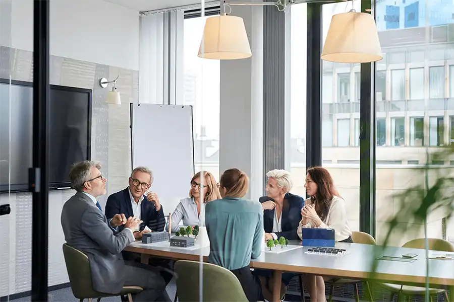 Providing Research, Delivering Clarity Three coworkers discussing plans written on a glass dry erase board