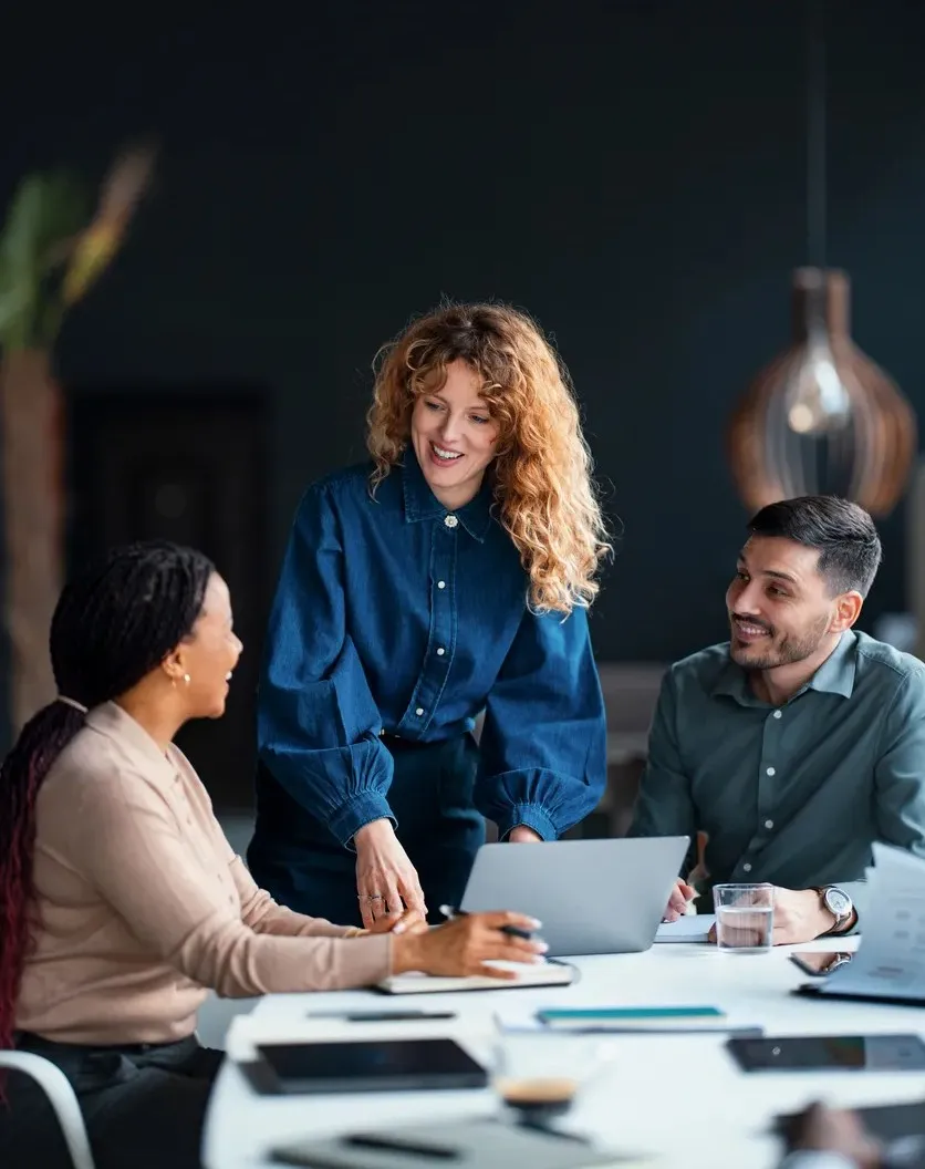 Three coworkers discussing plans written on a glass dry erase board